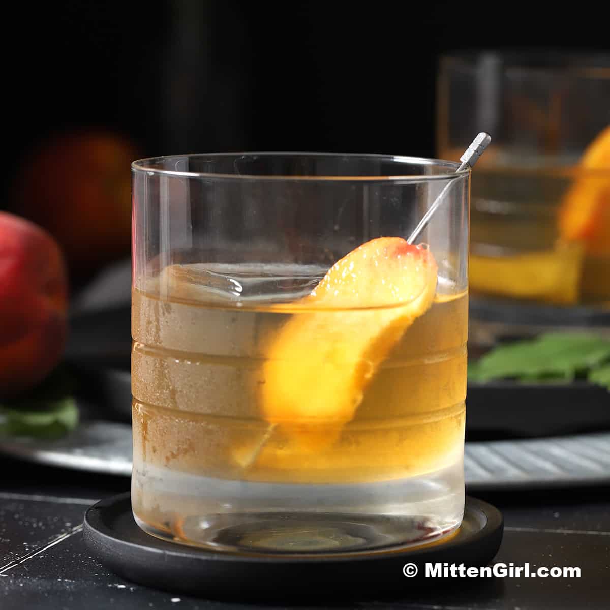 A glass of peach old fashioned cocktail.