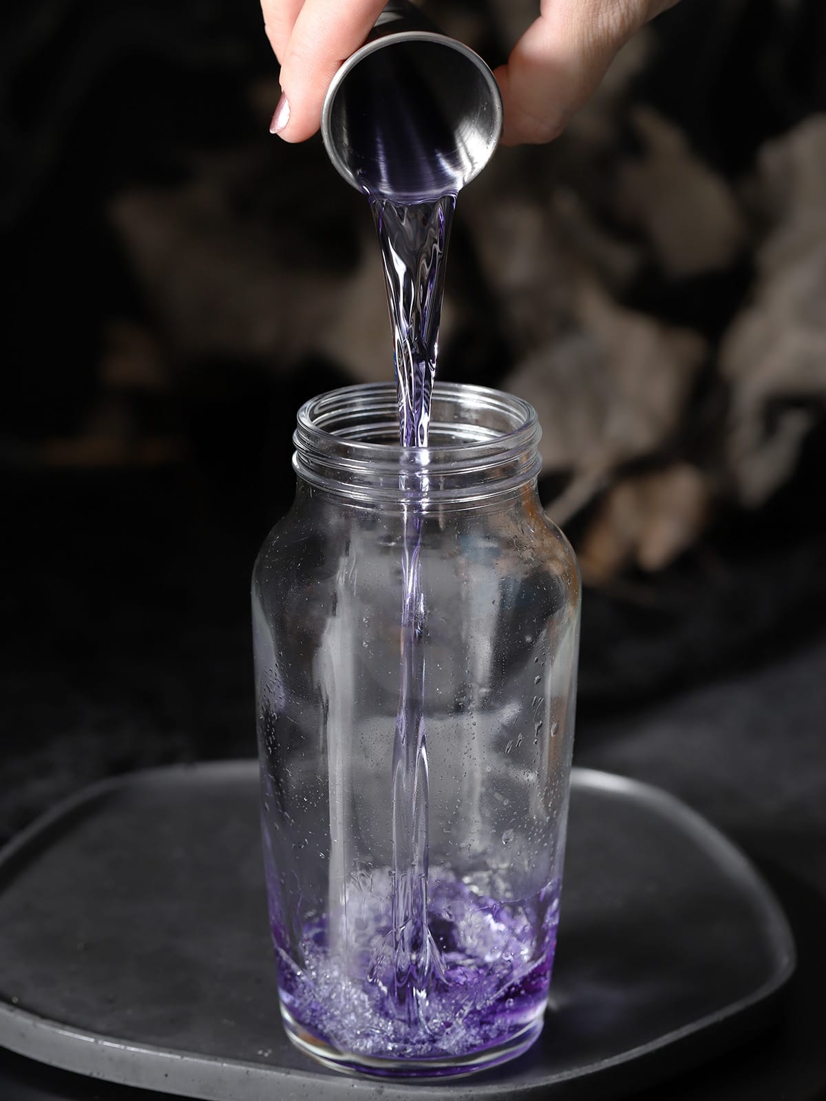 Indigo gin being poured into a cocktail shaker. 