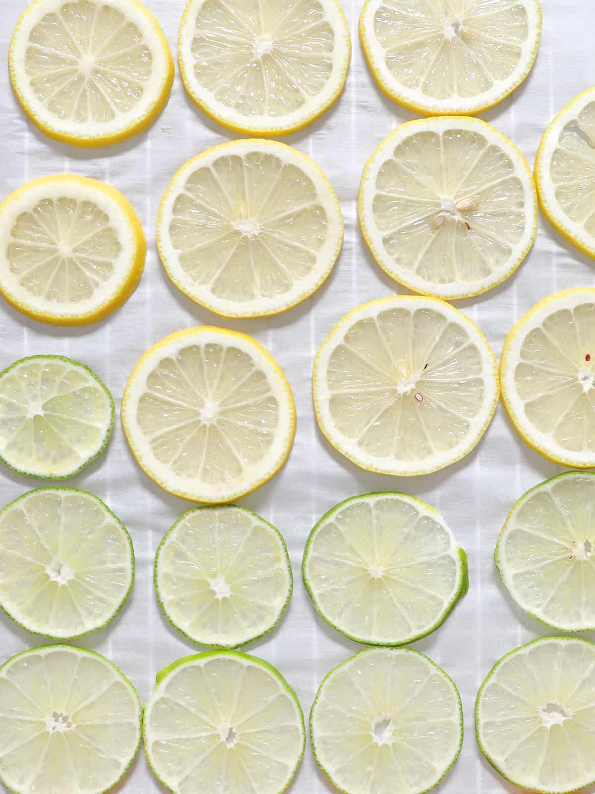 Slices of lemons and limes arranged on a sheet of parchment paper. 