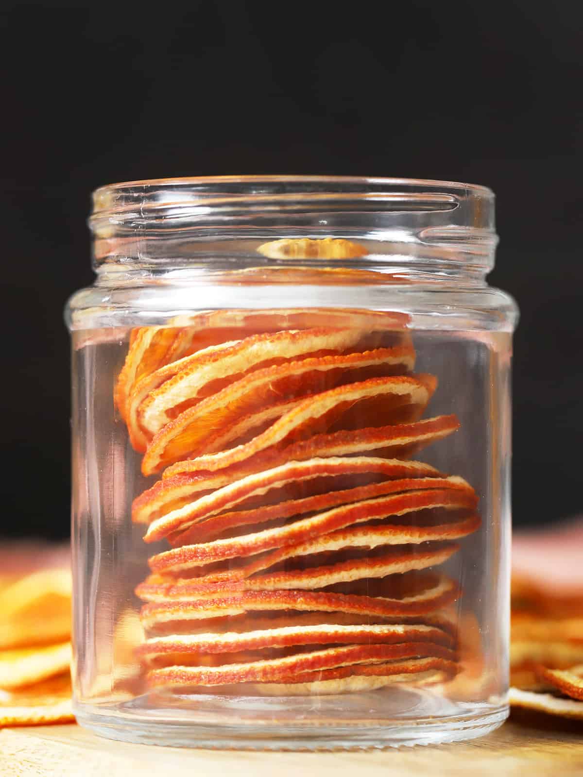 A glass jar filled with dried orange slices. 