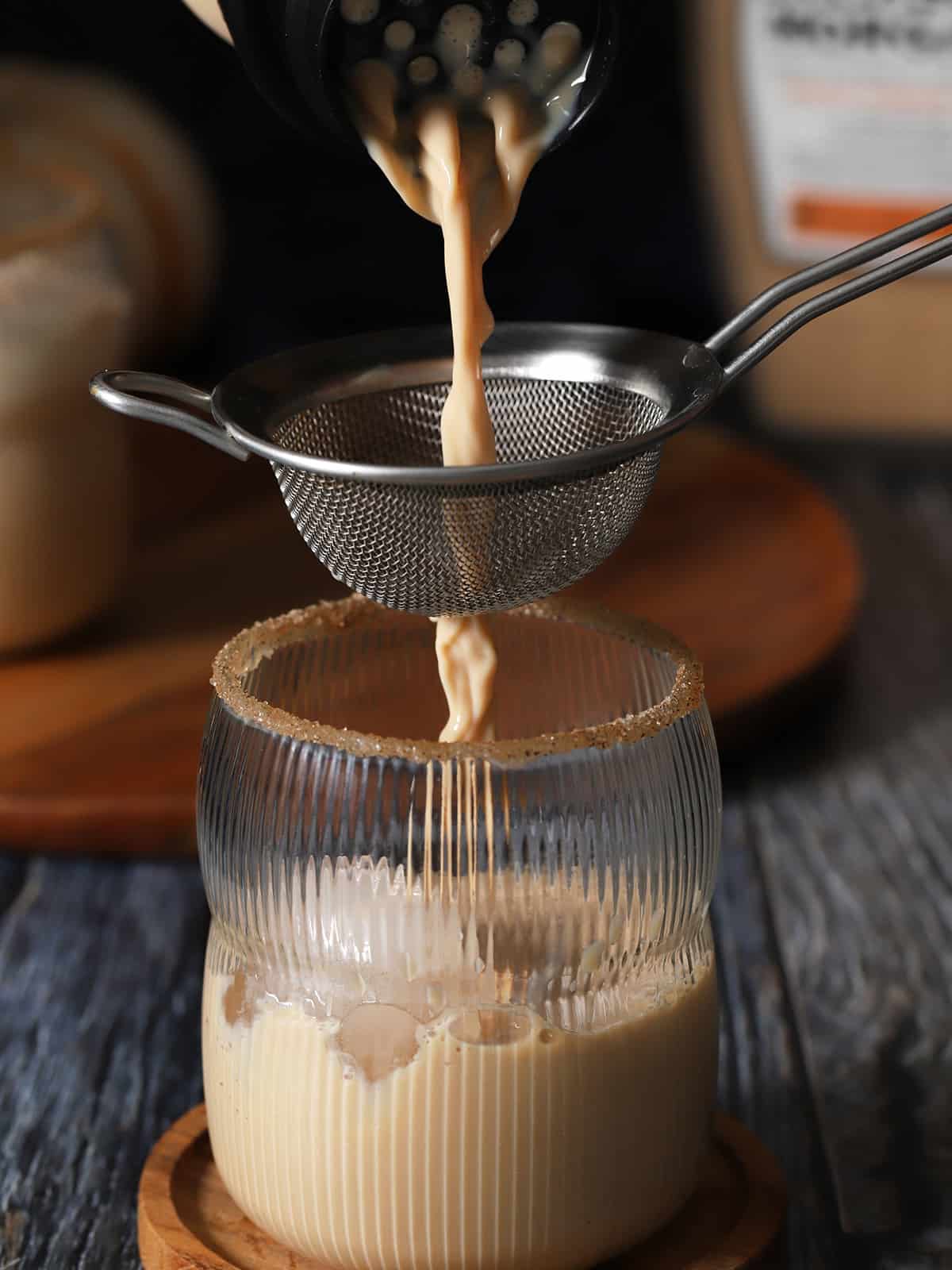 Pumpkin Spice white Russian cocktail being poured through a strainer and into a glass. 