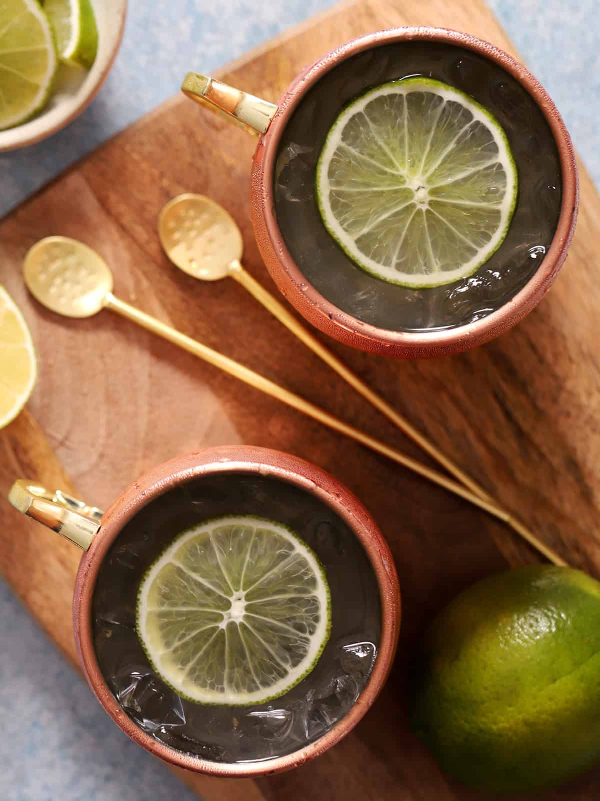 Copper mugs filled with cocktail and garnished with lime slices.