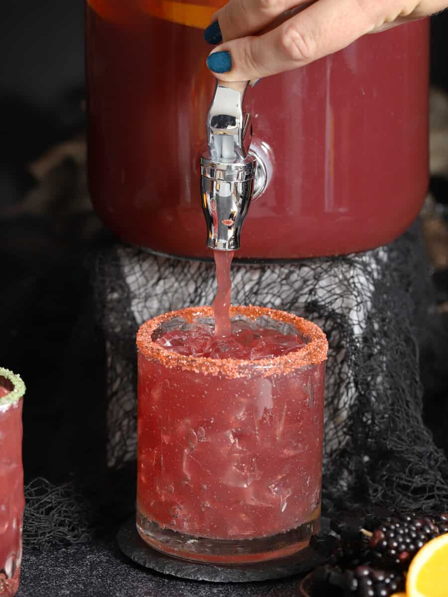 Non-Alcoholic Halloween Punch being poured into a sugar-rimmed glass.