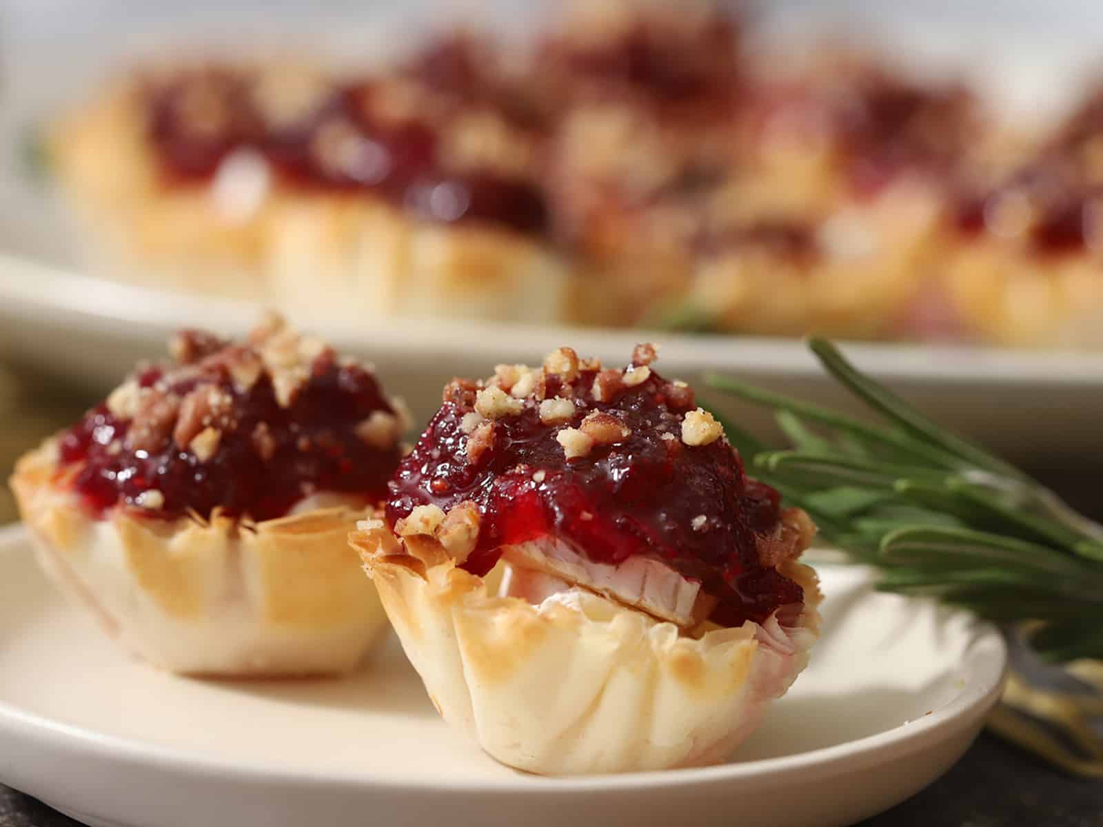 A small plate of Brie and Cranberry Bites with a larger platter in the background.