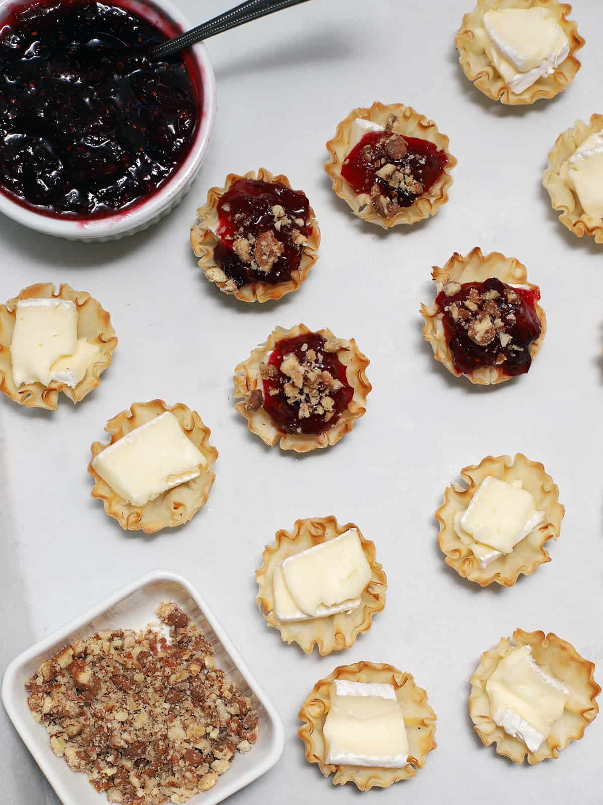 Chopped nuts on top of phyllo cups of brie cheese and cranberry sauce. 