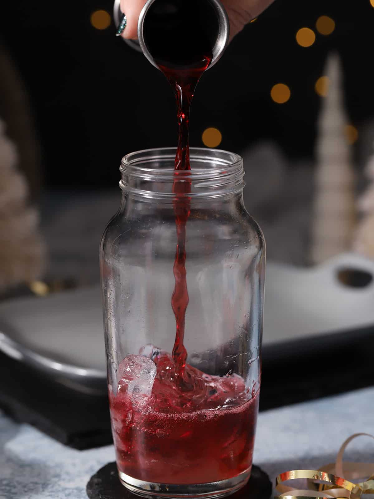 Cherry juice being poured into a cocktail shaker. 