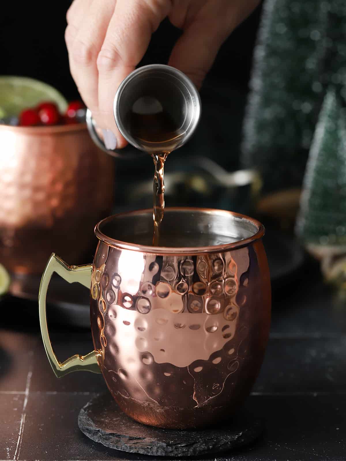 Cranberry juice being poured into a copper mug.