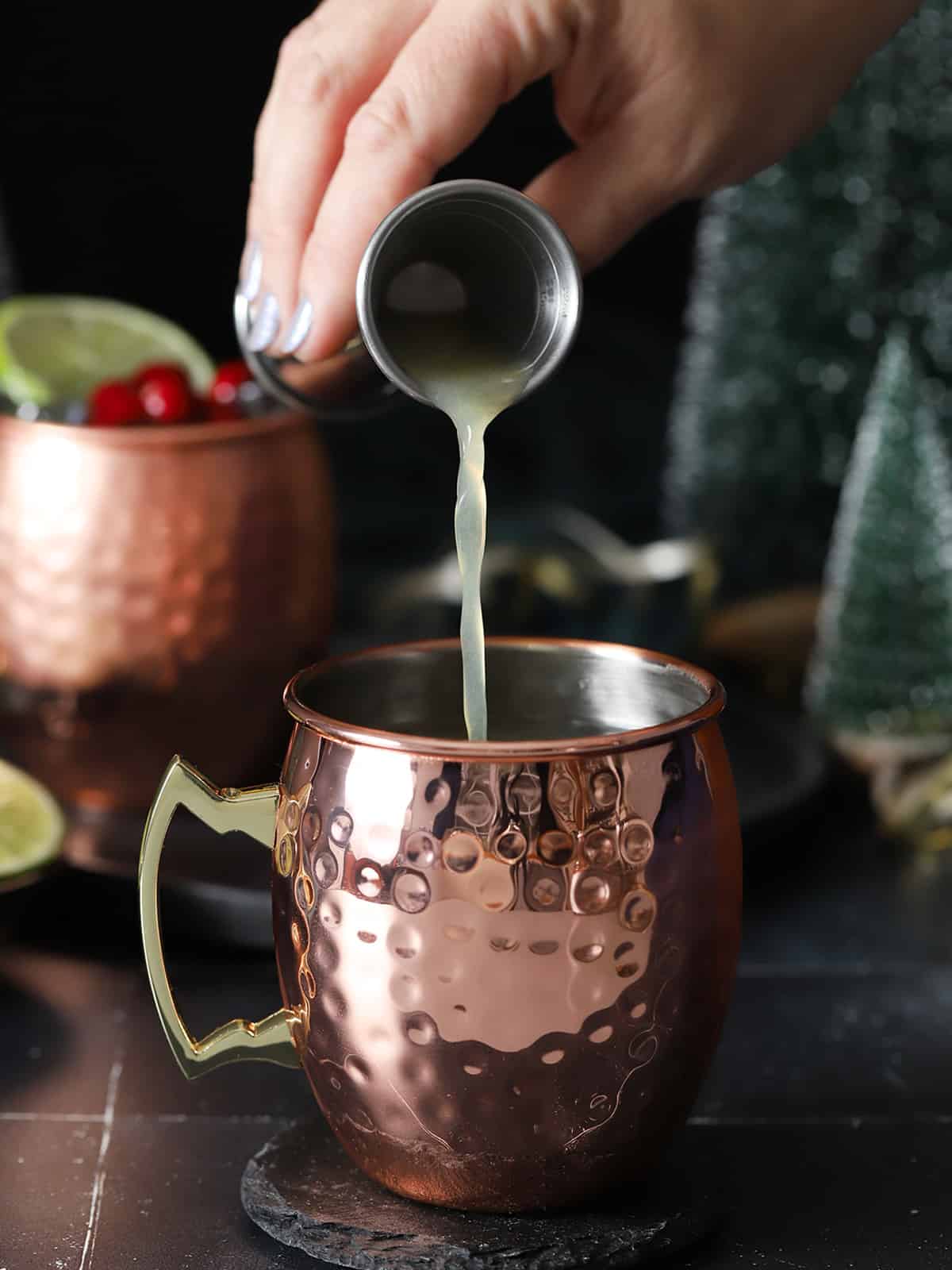 Lime juice being poured into a copper mug. 