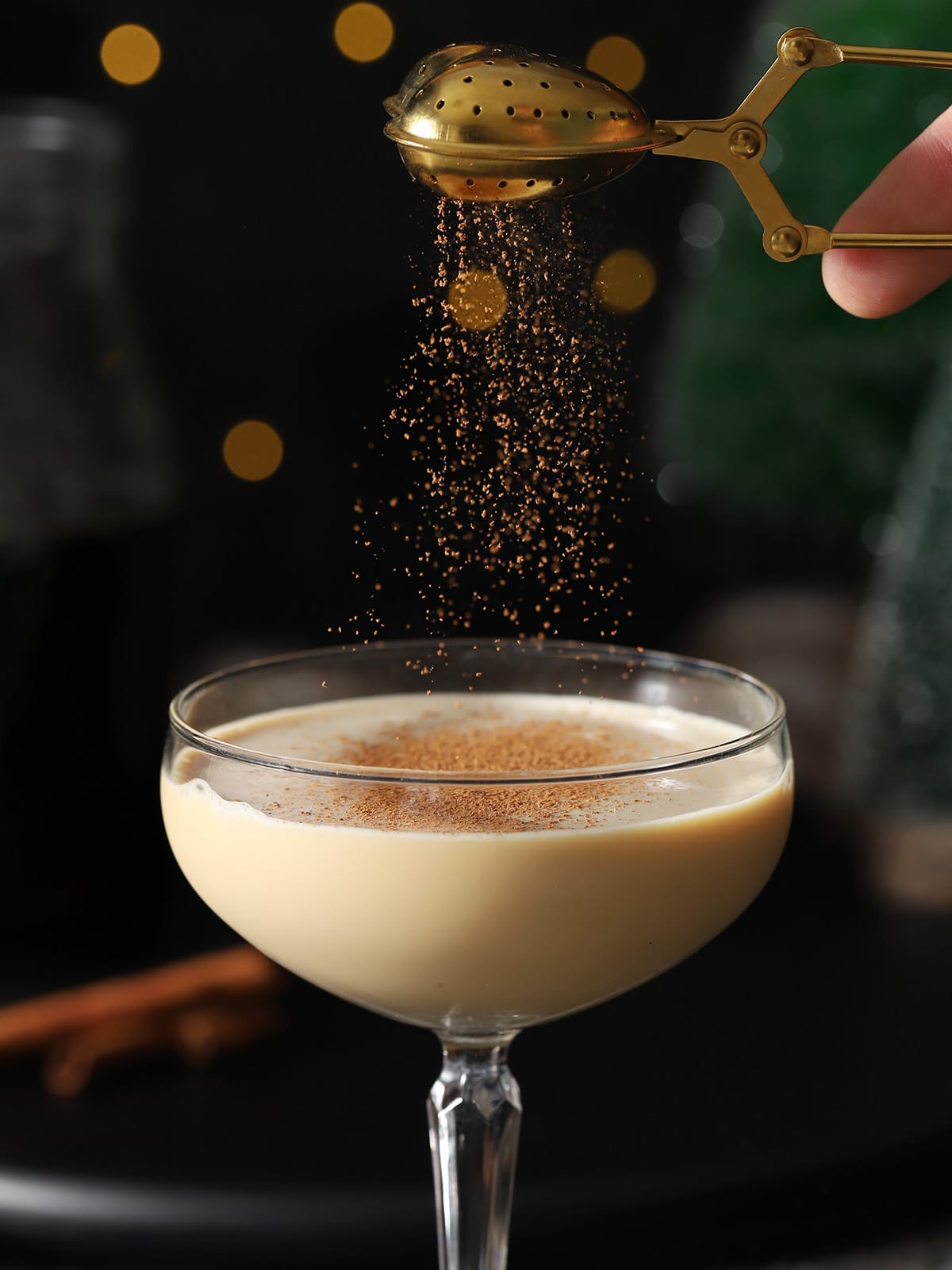 Cinnamon being sprinkled onto a gingerbread martini. 