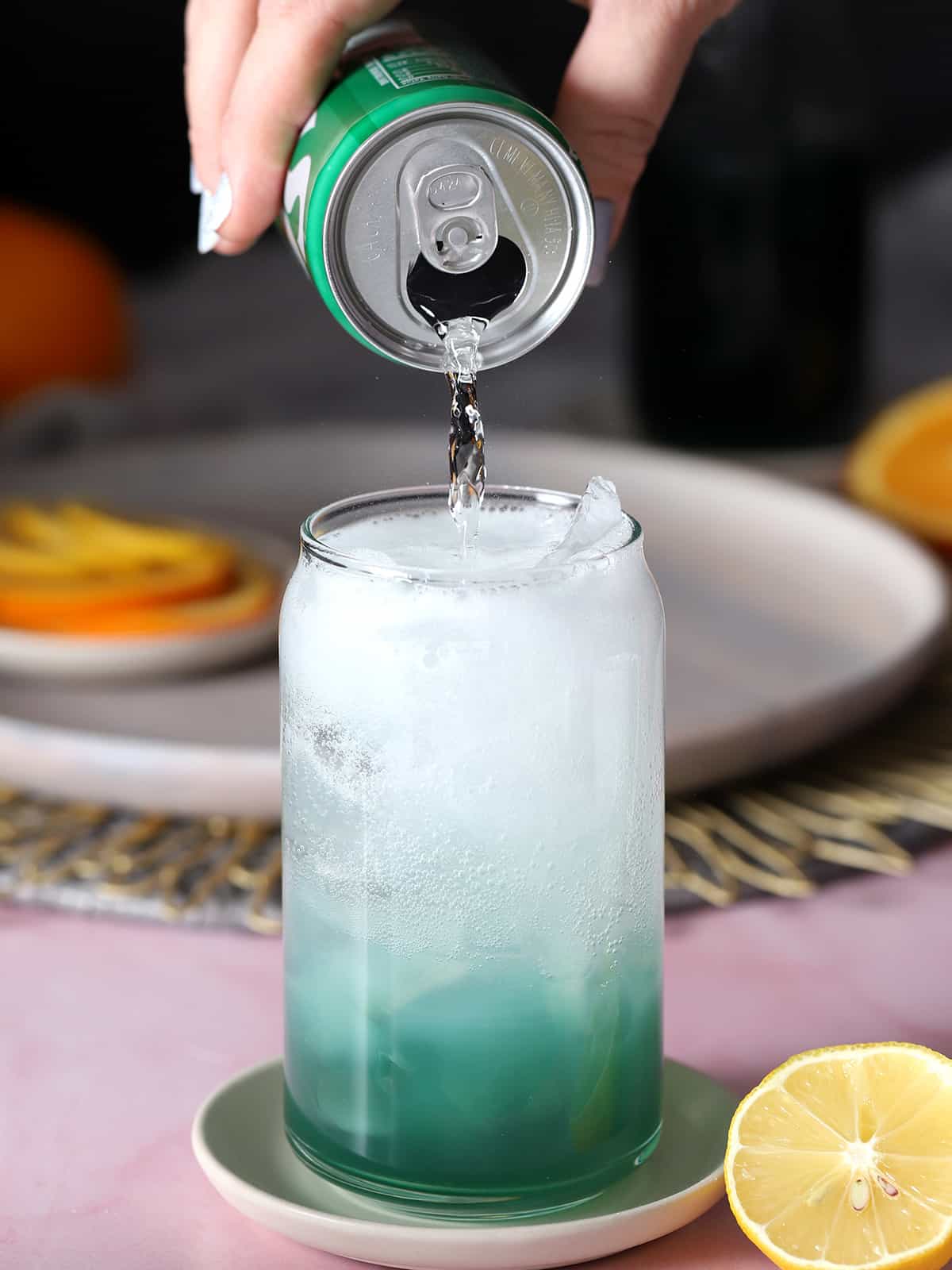 Lemon lime soda being poured into a glass for a blue lagoon mocktail.