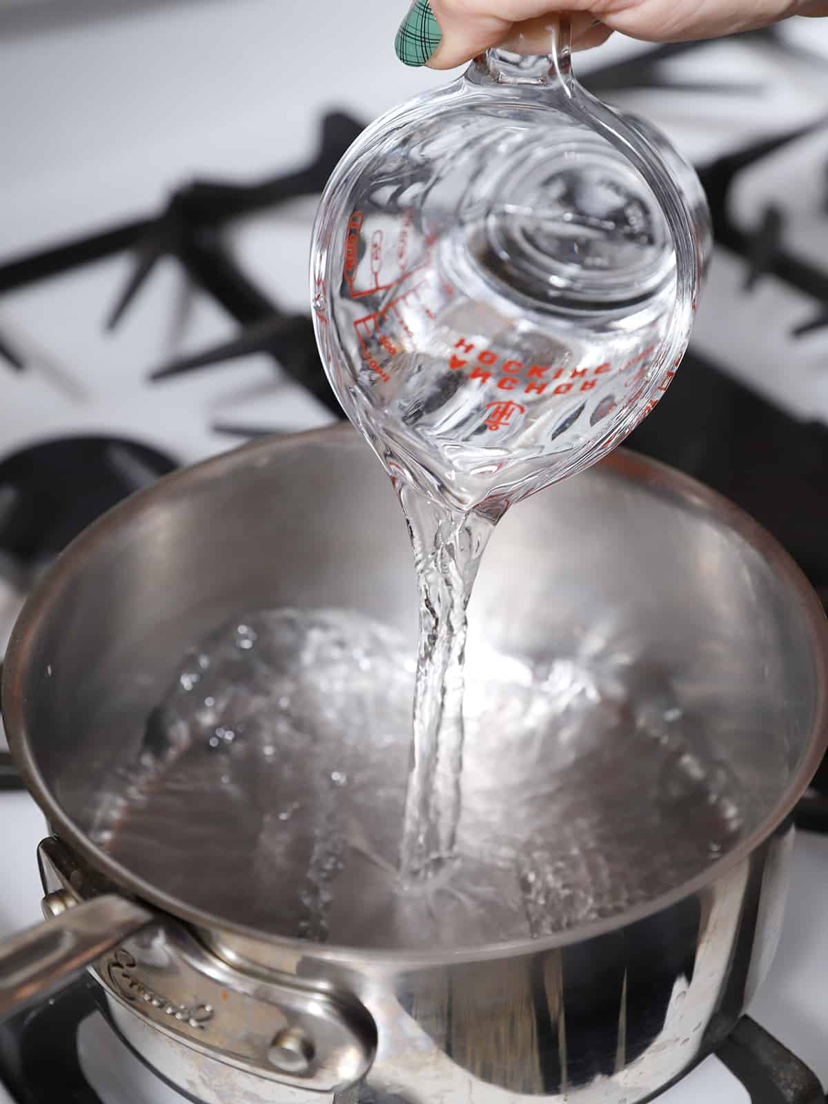 Water being poured into a pan on the stove. 