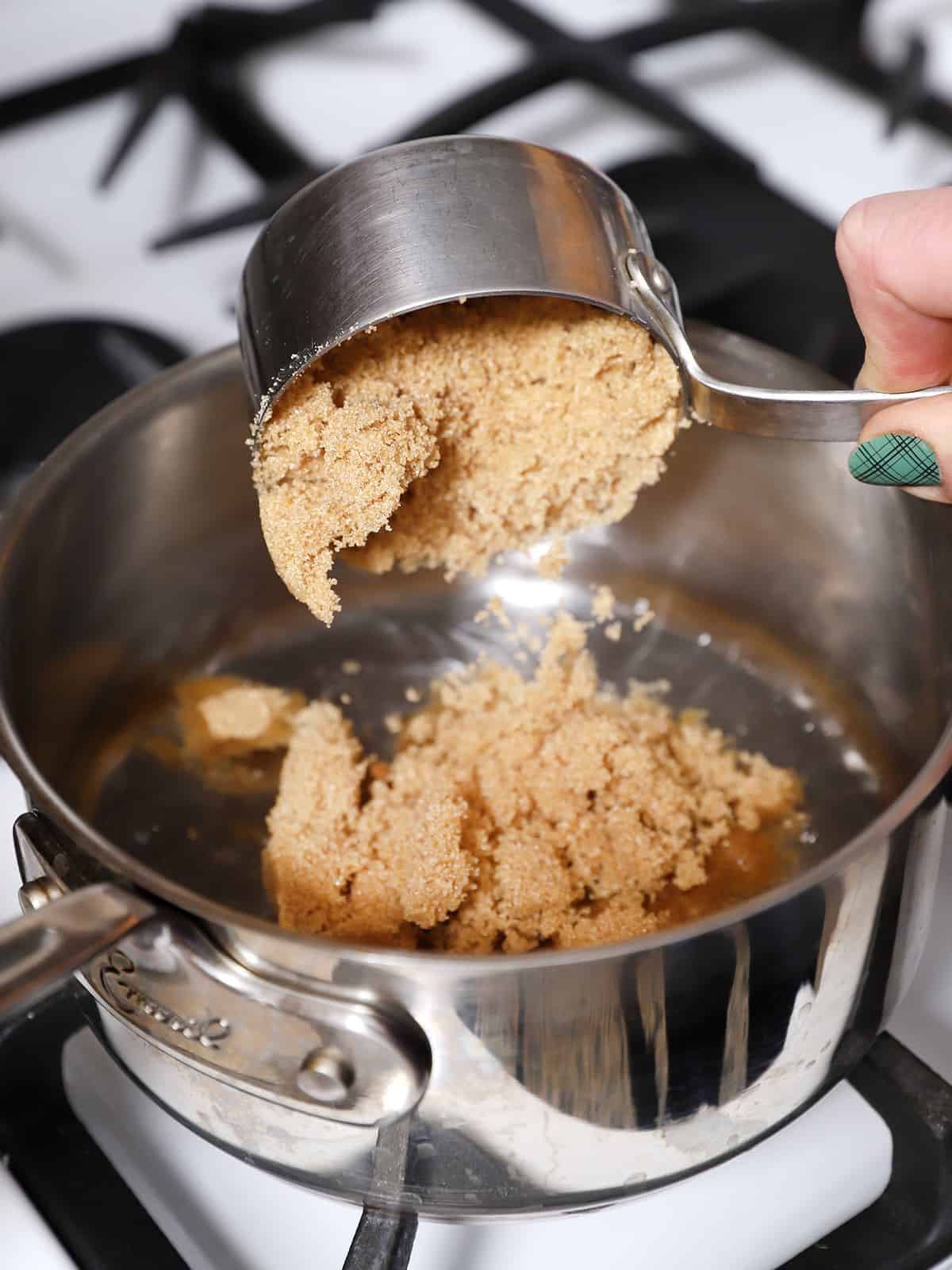 Brown sugar being poured into a pot. 