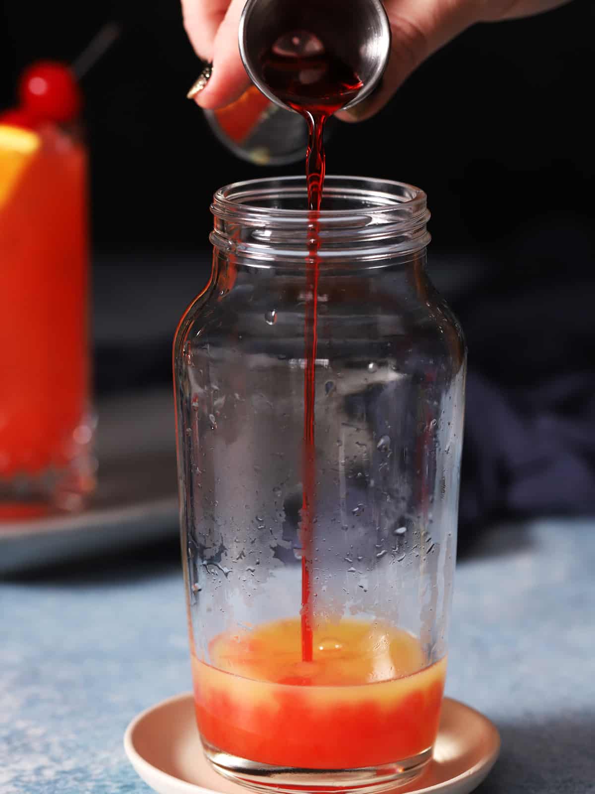 Grenadine being poured into a cocktail shaker. 