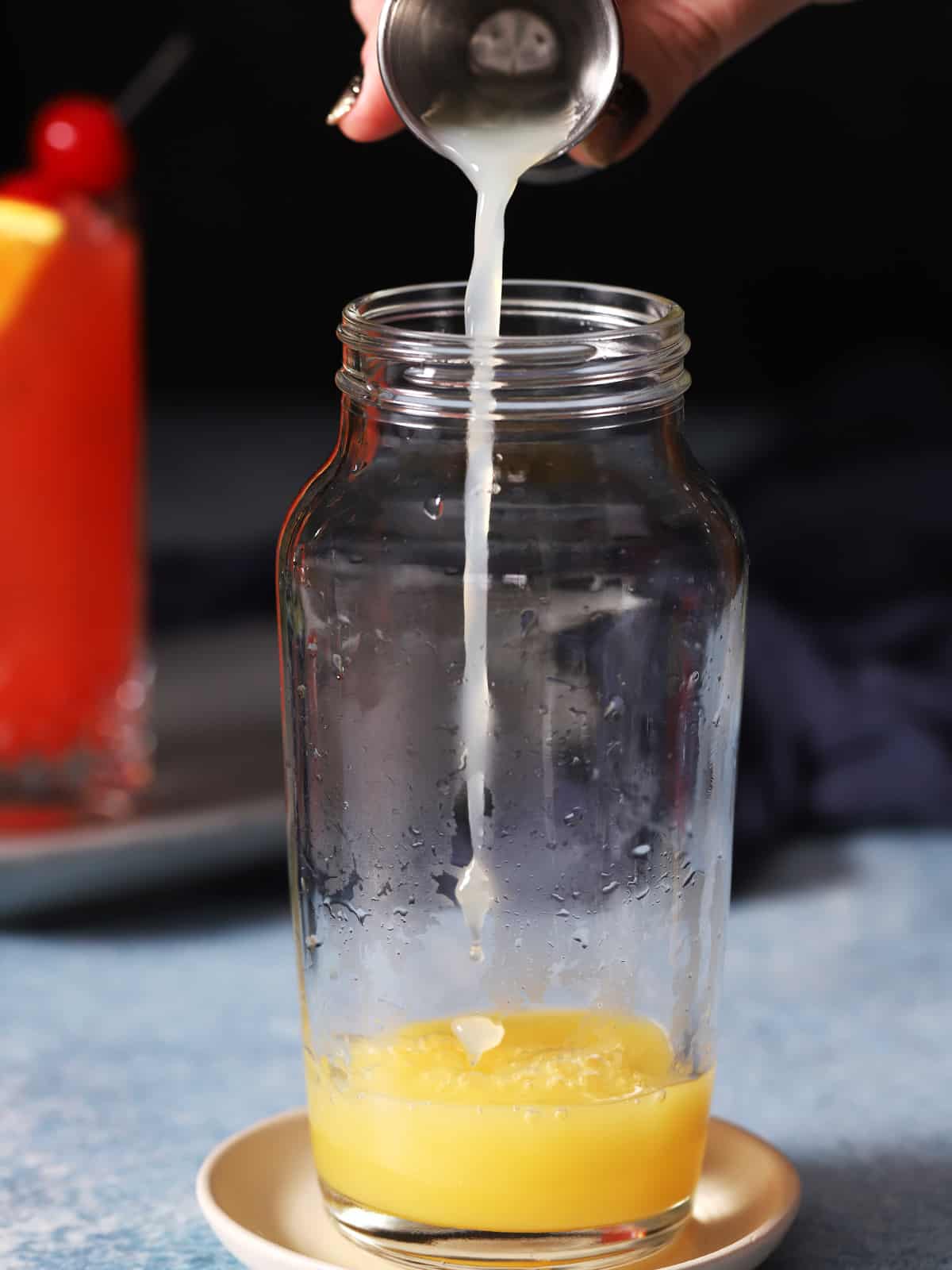Lemon juice being poured into a cocktail shaker. 