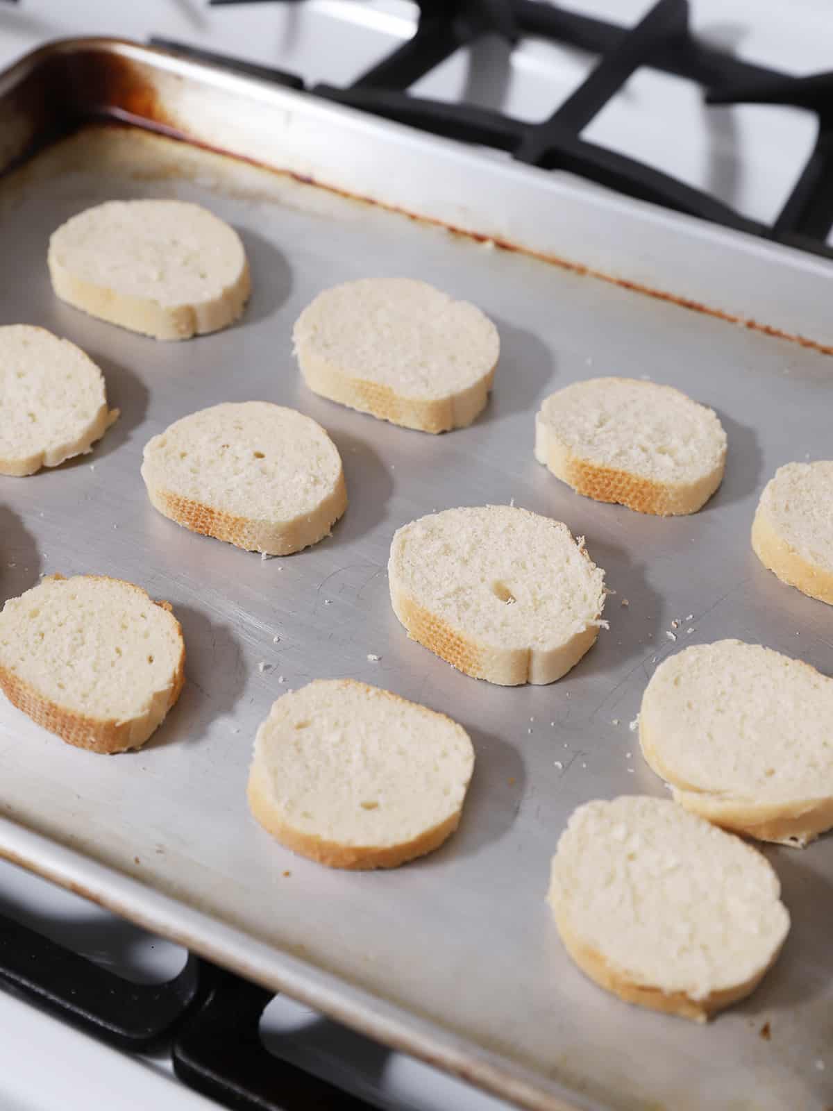 Slices of French bread on a baking sheet. 