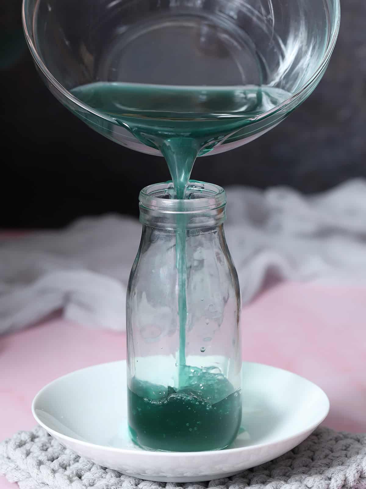 Blue Curaçao syrup being poured into a glass jar.