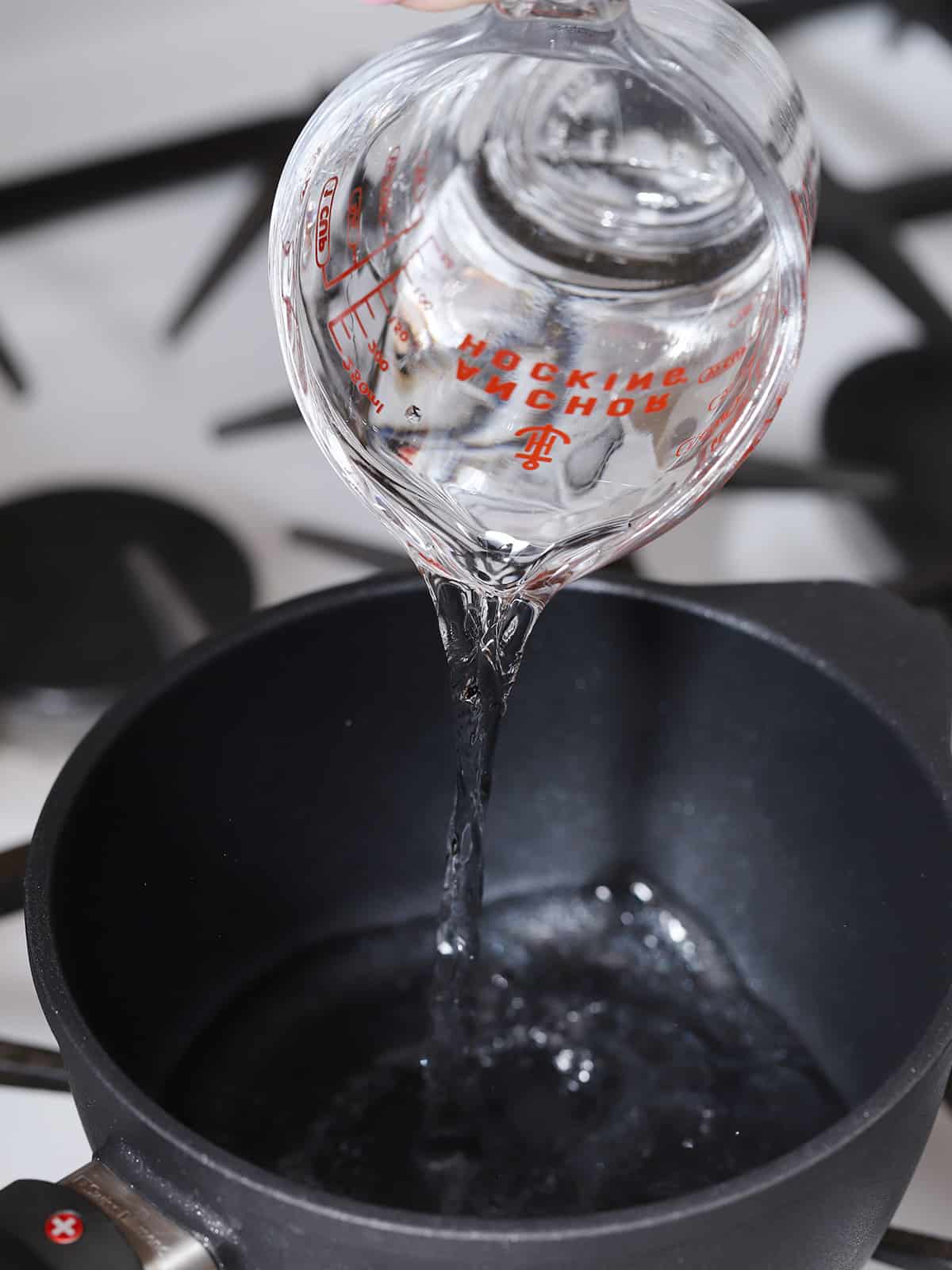 Water being poured into a pot on the stove. 