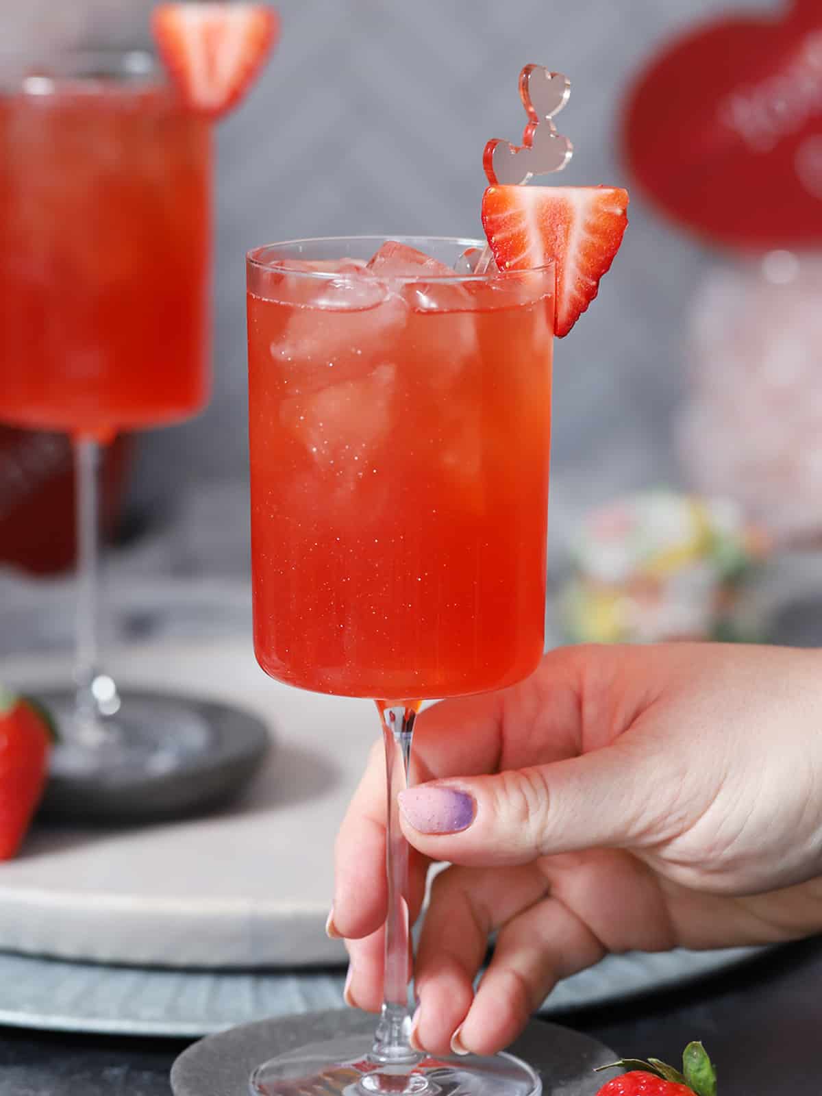 A hand picking up a glass of Love Potion drink mocktail. 