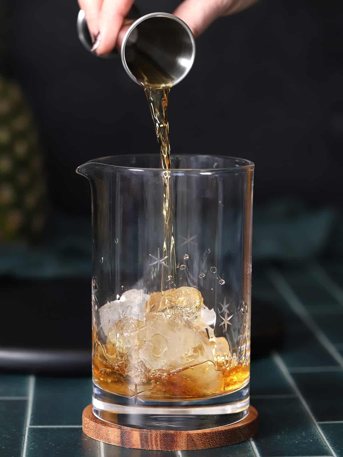 Bourbon being poured into a mixing glass with ice. 