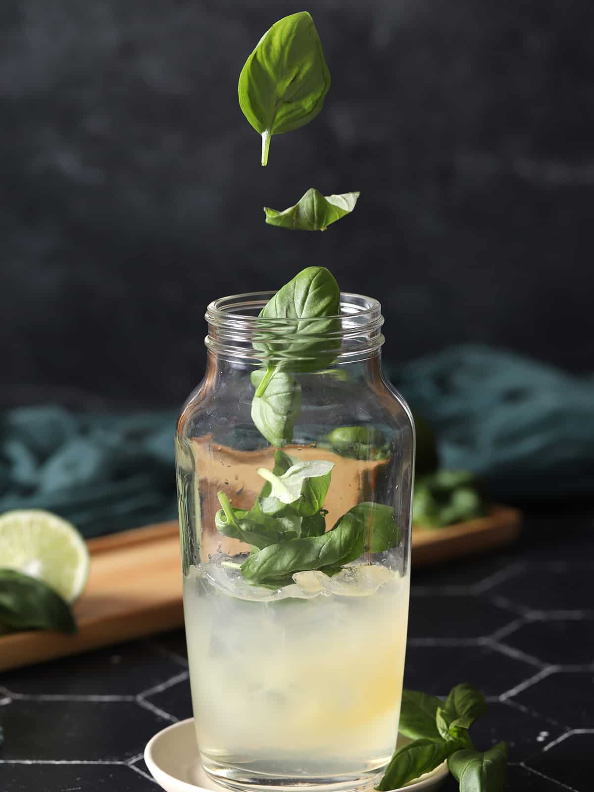 Basil leaves being dropped into a cocktail shaker. 