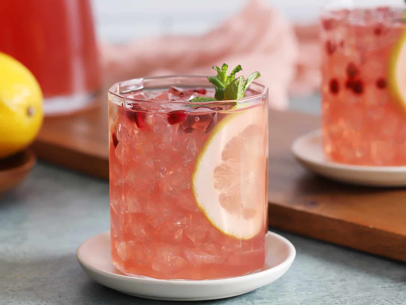 A glass of pomegranate lemonade garnished with a slice of lemon.