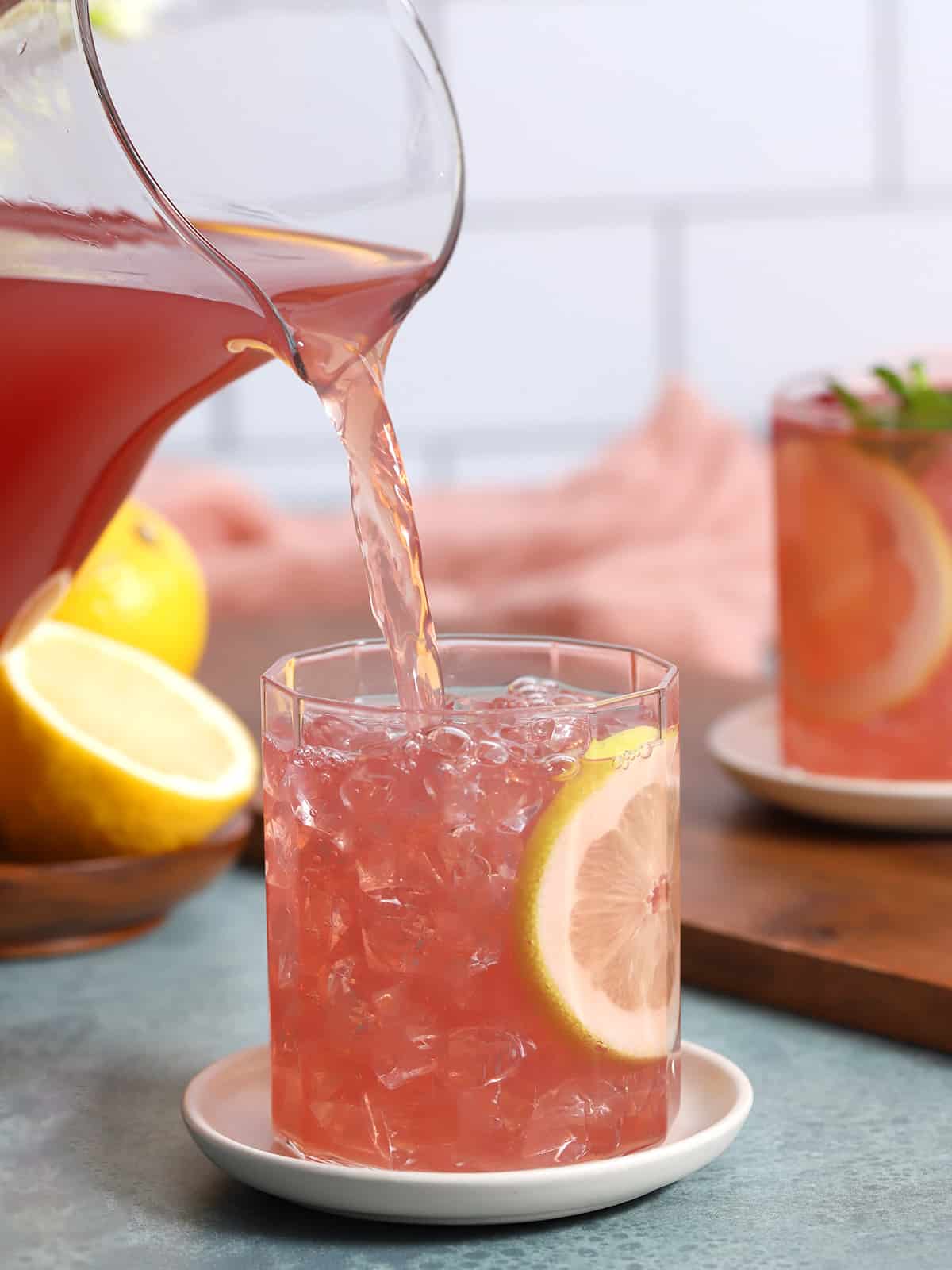 Pomegranate lemonade being poured into a glass. 