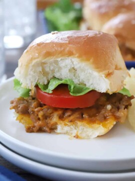 A cheeseburger slider with tomato and lettuce.