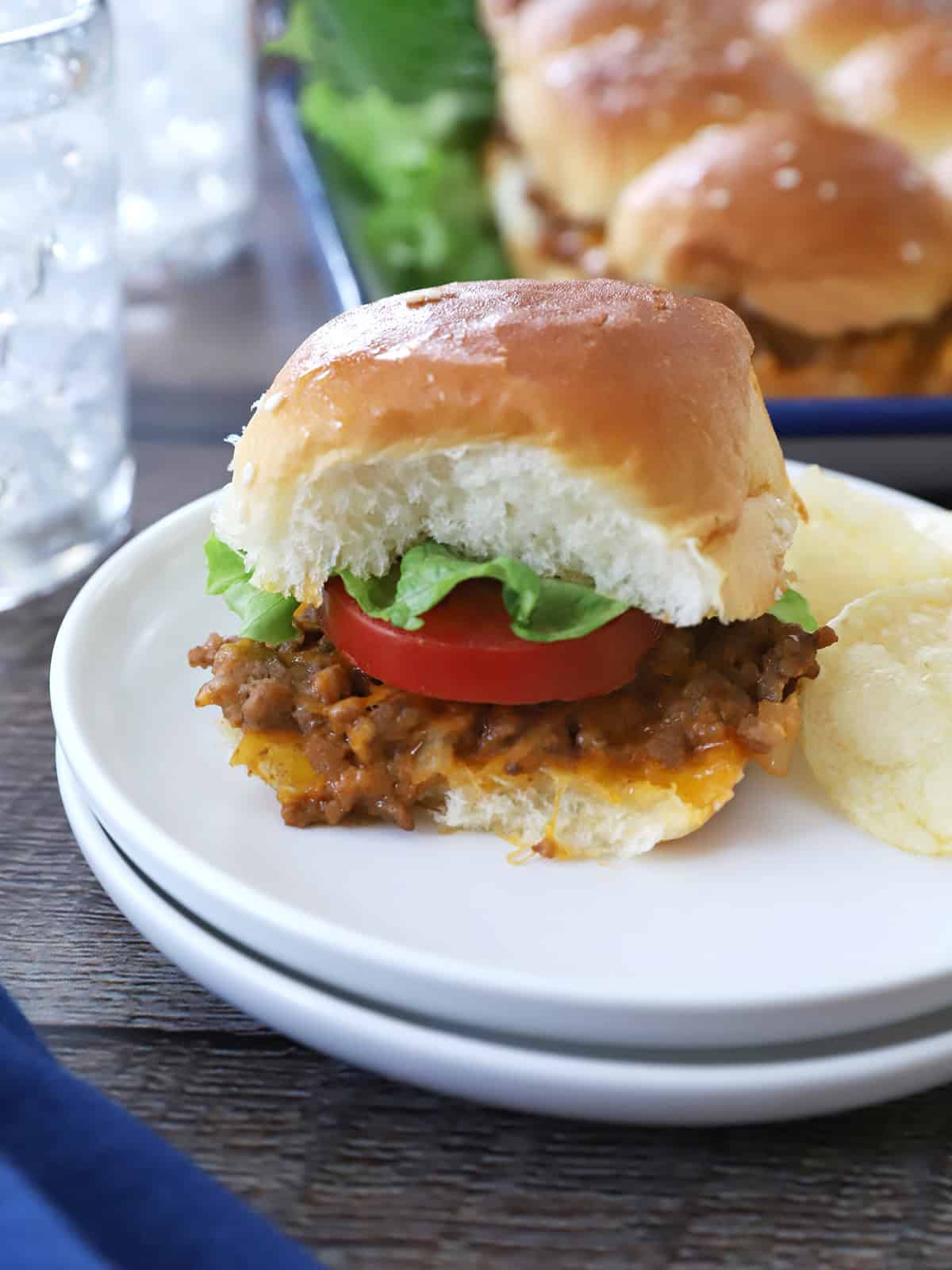 A cheeseburger slider with tomato and lettuce.