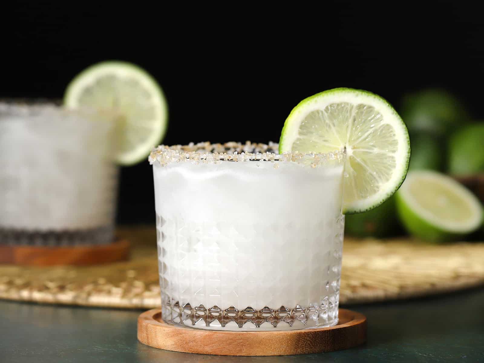 Glasses of coconut margarita garnished with lime wheels.