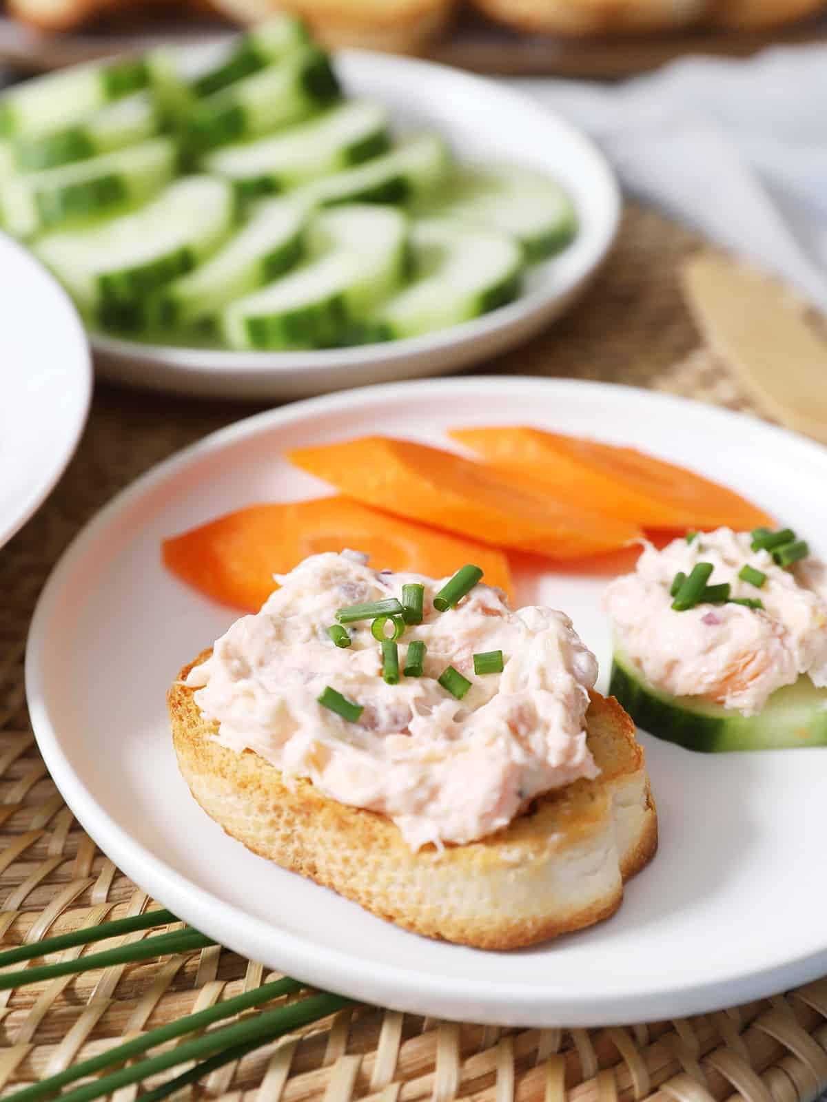 A plate with smoked salmon crostini and bread and a cucumber slice. 