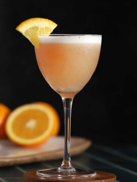 A glass of cranberry orange whiskey sour cocktail.