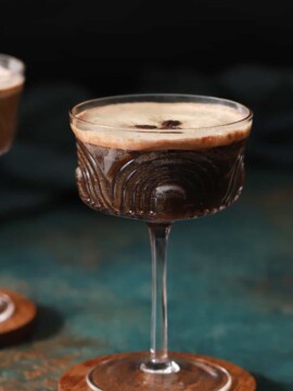A pair of espresso martini mocktails on wooden coasters.