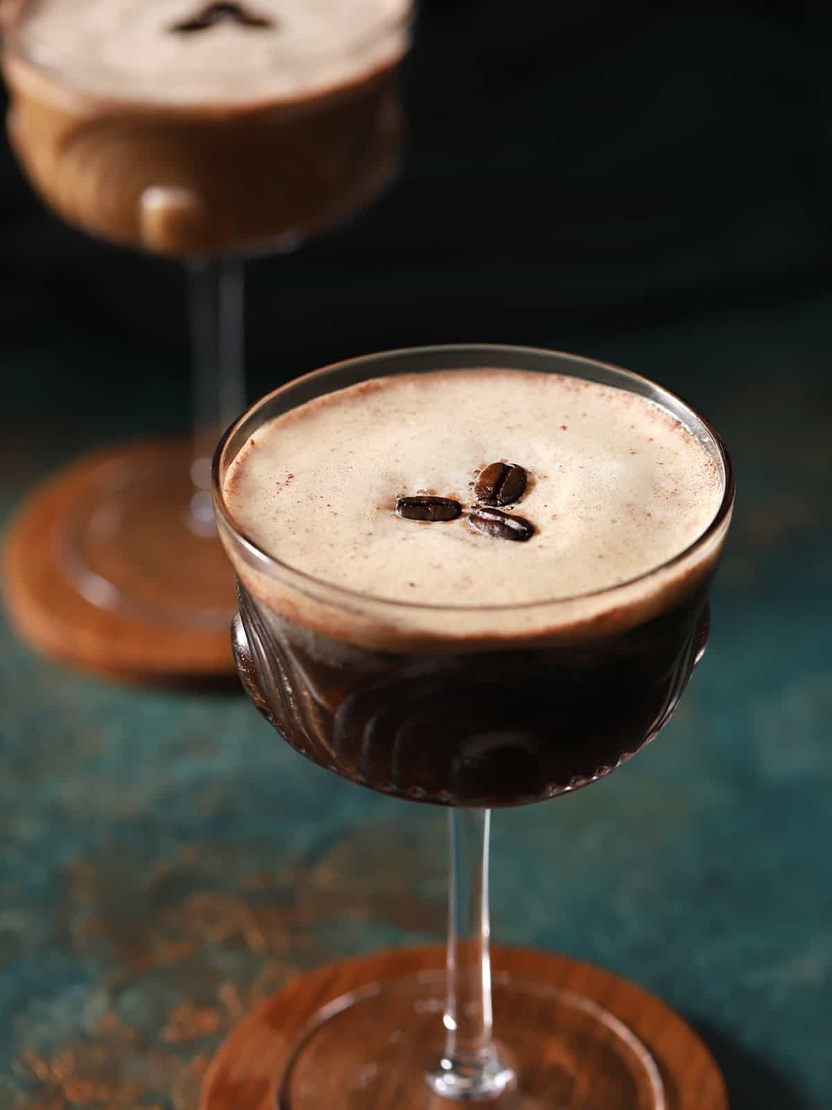 A glass of espresso martini mocktail garnished with 3 coffee beans.