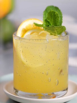 A glass of citrus punch mocktails garnished with fresh mint.