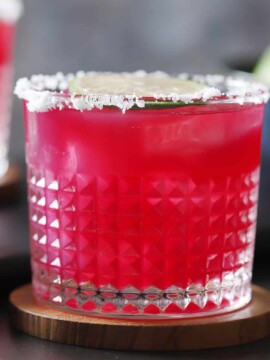 A glass with a salted rim filled with blueberry margarita.