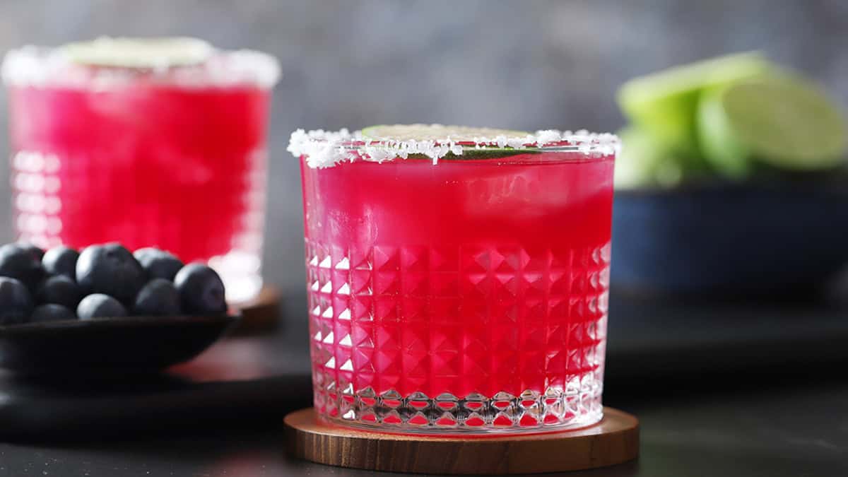 Glasses with salted rims filled with blueberry margaritas.