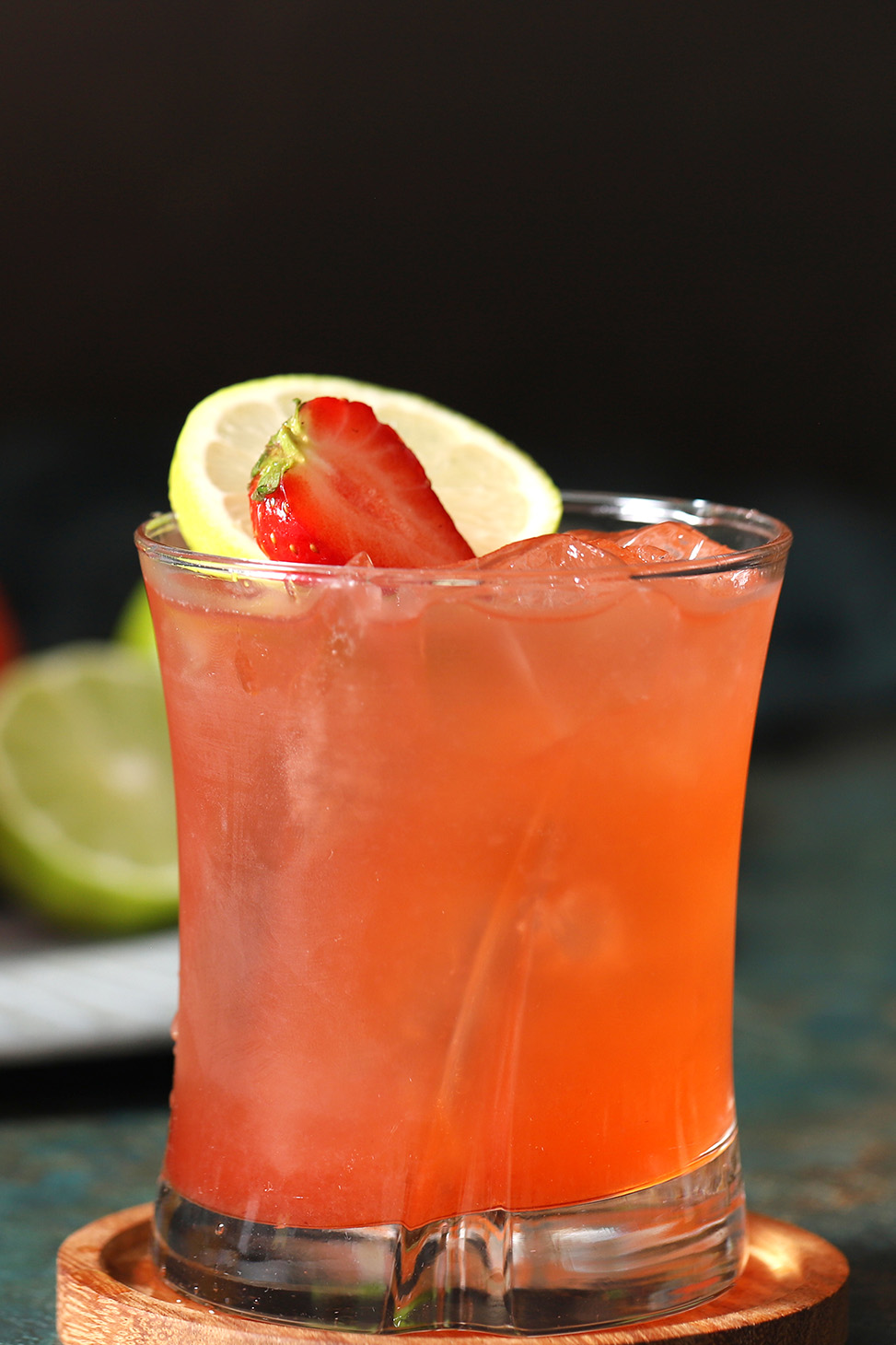 A glass of strawberry limeade mocktails garnished with fresh strawberries and slices of limes.
