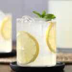 A glass of lemonade garnished with lemon slices and a sprig of mint.