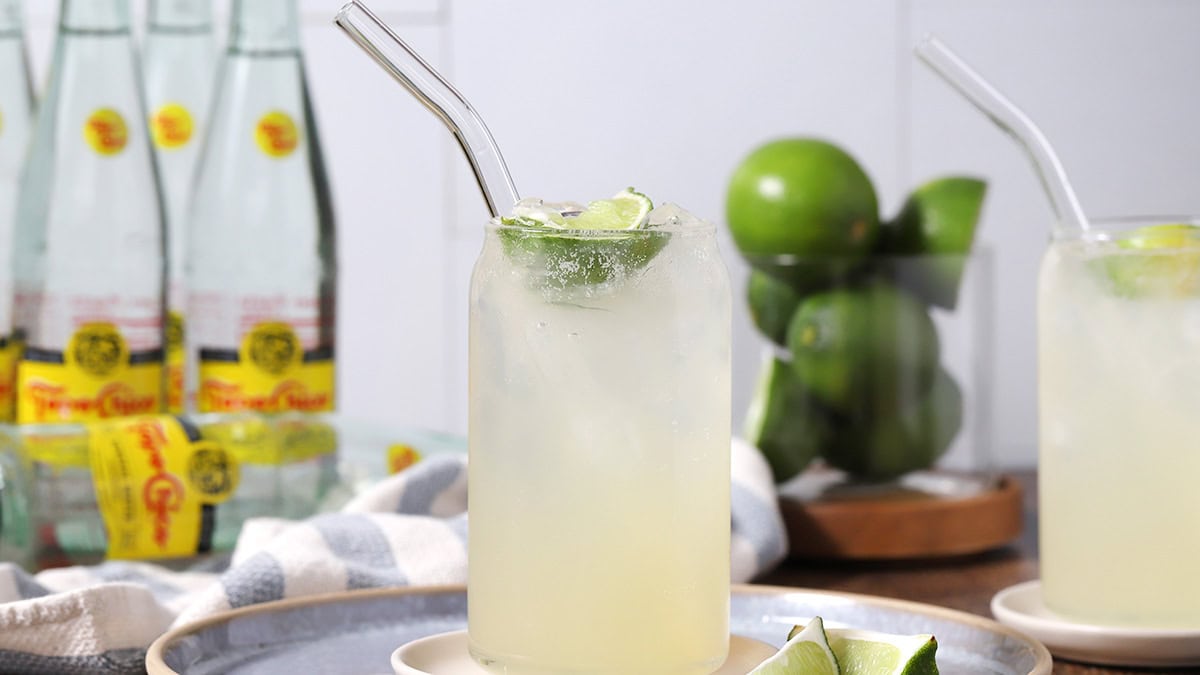 Glasses of ranch water surrounded by bottles of Topo Chico and fresh limes.