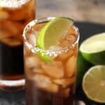 A glass of batanga cocktail garnished with a lime wedge and salted rim.