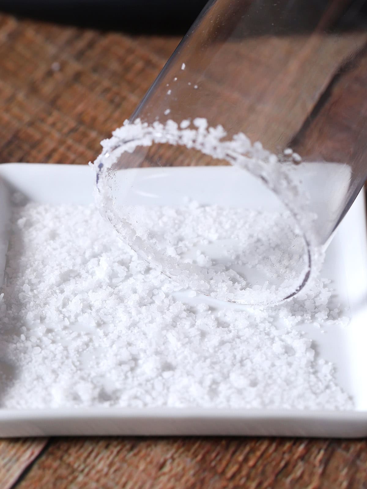The rim of a glass dipped in to a plate of coarse salt.