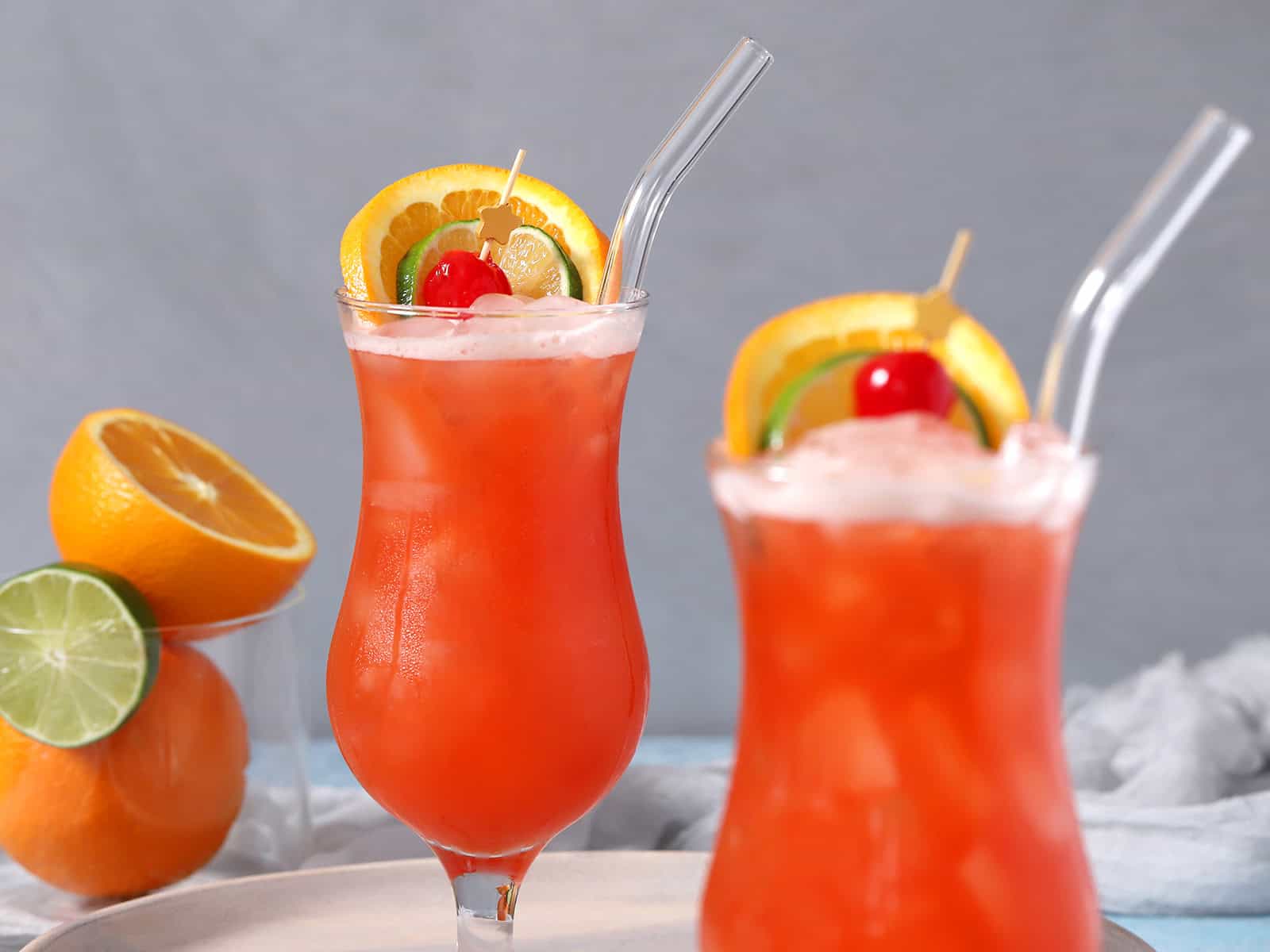 A pair of hurricane glasses filled with rum punch and garnished with fresh fruit.