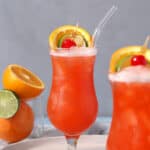 A pair of hurricane glasses filled with rum punch and garnished with fresh fruit.