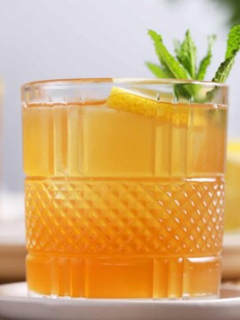 A glass of spiked arnold palmer cocktail garnished with lemon and mint.