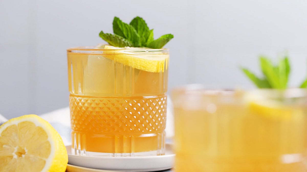 Glasses of spiked arnold palmer cocktail garnished with lemon and mint.