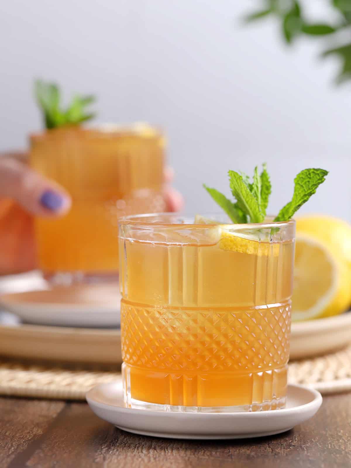 Glasses of spiked arnold palmer cocktail garnished with lemon and mint.