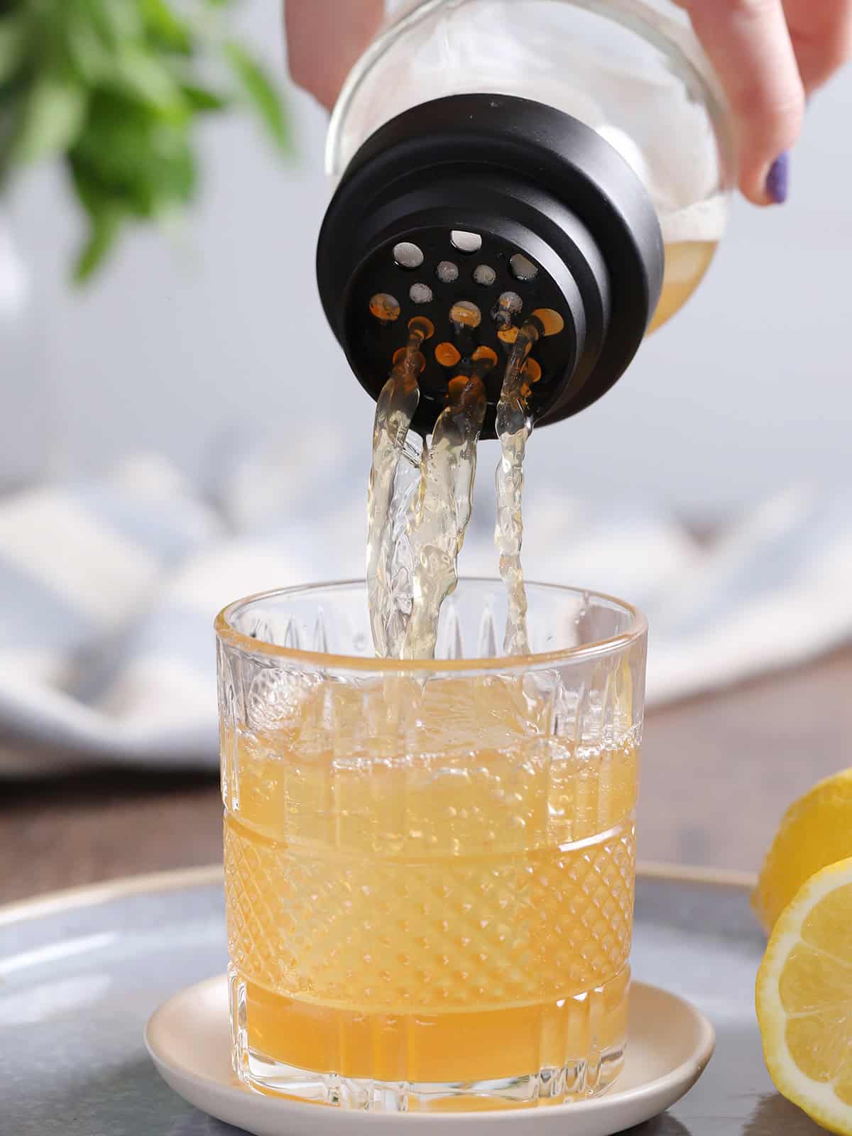 Spiked Arnold Palmer cocktail being poured from a shaker into a rocks glass filled with ice.