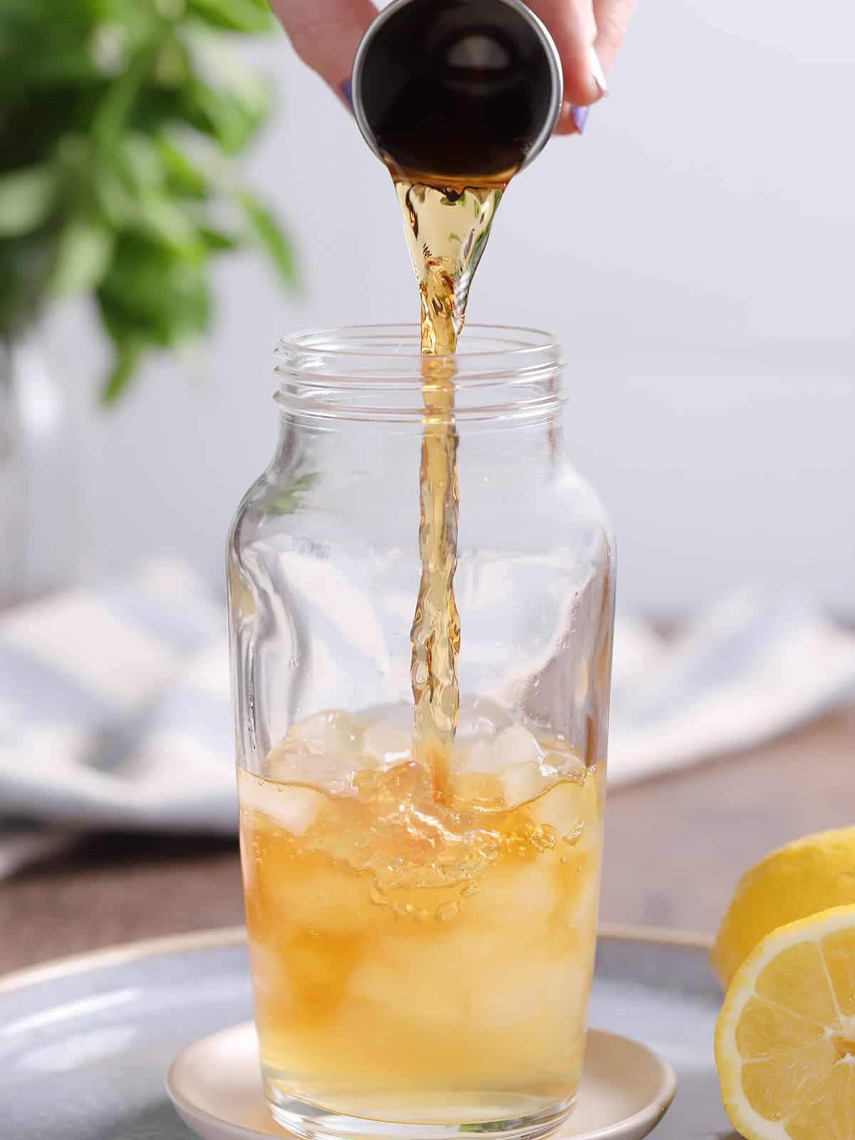 Iced tea being poured from a jigger into a cocktail shaker.