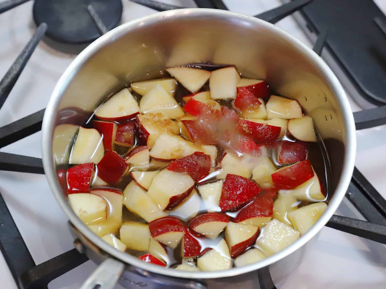 Apples, water, and sugars in a pot on the stove.