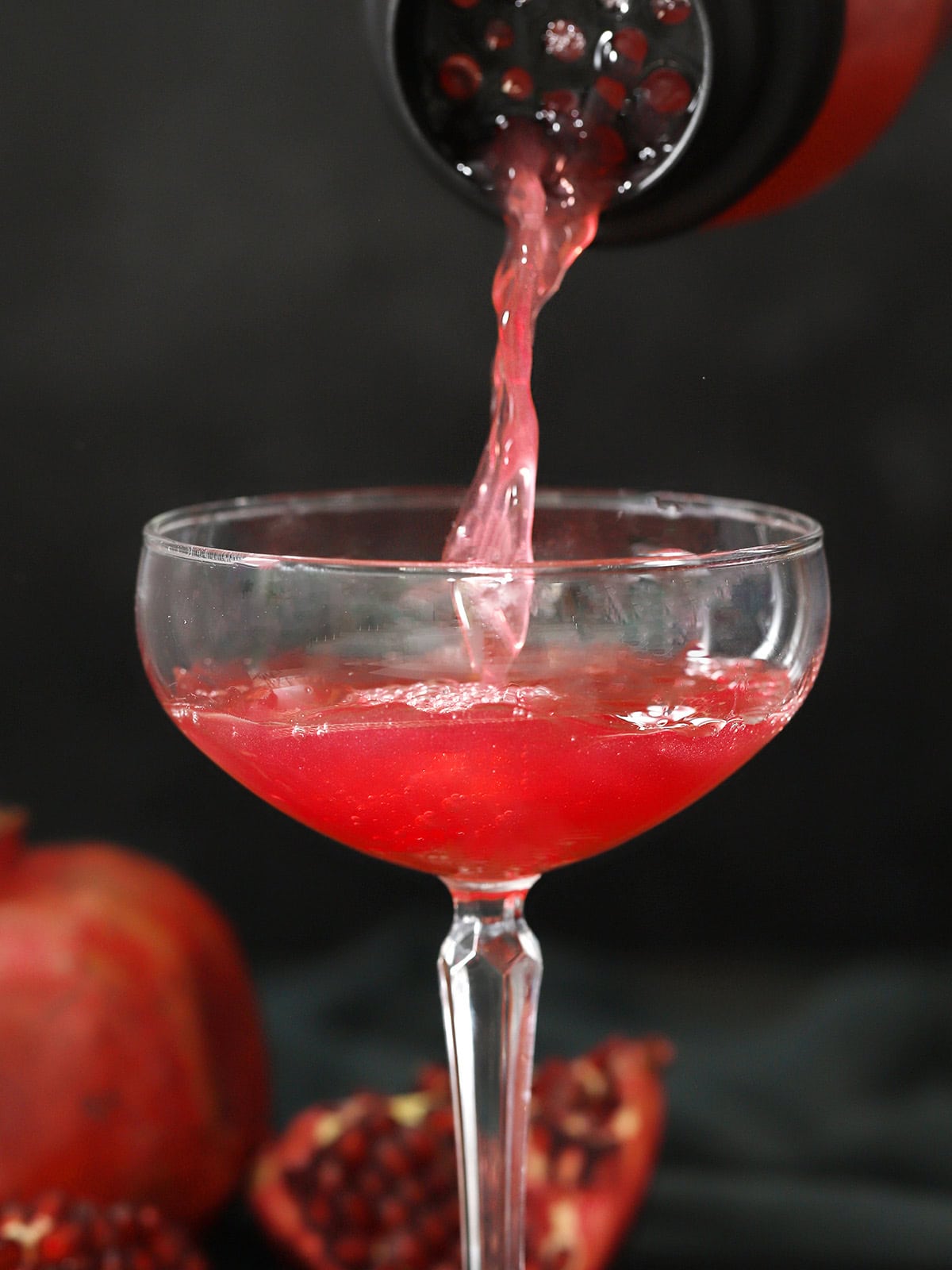 Pomegranate martini being poured into a coupe glass.